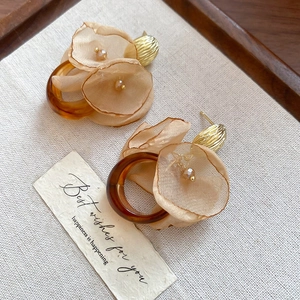 Detailed close-up of elegant fabric chiffon flower earrings with amber resin accents