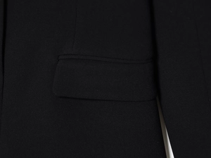 Detailed view of the flap pocket and fine stitching on a black blazer dress