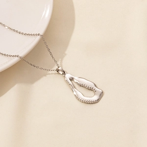 Macro view of silver organic hollow pendant with beaded edges and polished surface