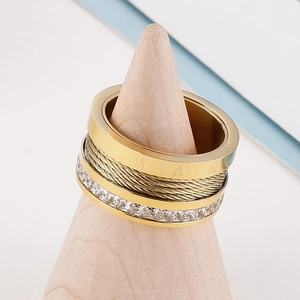 Macro detail of gold-plated roman numeral ring with cable texture and zircon stones
