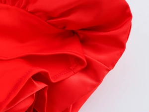 Détail d'une robe rouge à col carré montrant la texture soyeuse du tissu et les coutures fines