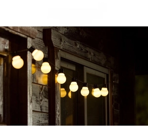 Detail of G50 solar string lights with warm white LED bulbs hanging on wooden house
