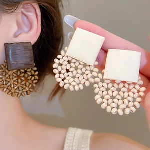 Detail of large geometric wood drop earrings with handcrafted woven circular beads