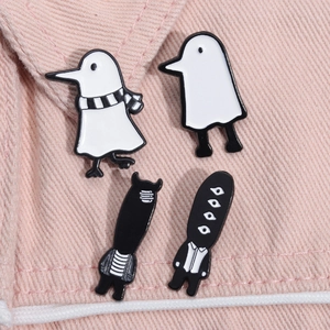 Close-up of four cute black and white enamel pins on pink denim fabric background