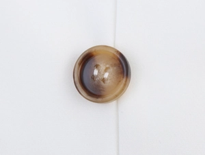 Macro shot of brown tortoiseshell buttons on white sleeveless vest fabric detail