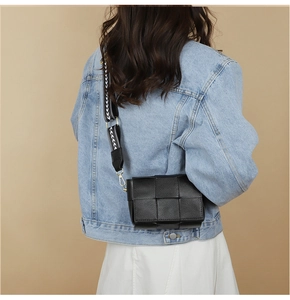 Model view of black woven leather crossbody bag with patterned wide shoulder strap