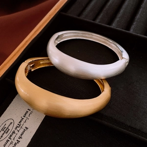 Vue détaillée des joncs ovales mats en or et argent brossé dans une boîte à bijoux