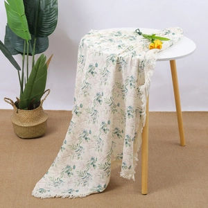 Detail of soft cotton baby blanket with green leaf prints and decorative white fringe