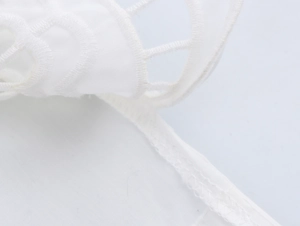 Détail de la broderie ajourée française blanche et couture dentelle sur haut sans manches