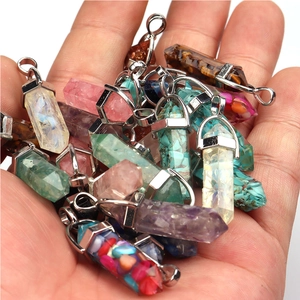 Multiple hexagonal amethyst and quartz bullet stone pendants held in hand with metal loops