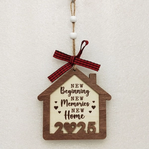 Close-up of wooden house ornament with 2025 New Home engraving and red plaid bow