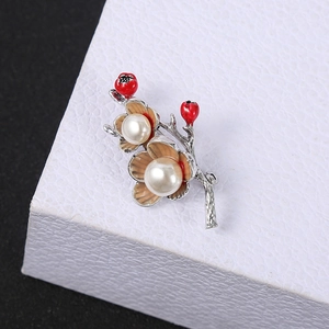 Macro detail of red floral brooch with white pearls on a textured jewelry box