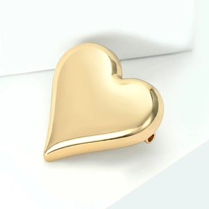Macro detail of polished gold heart brooch with focus on plating and pin buckle