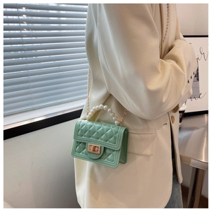 Detail of mint green quilted mini bag featuring pearl handle and gold chain strap