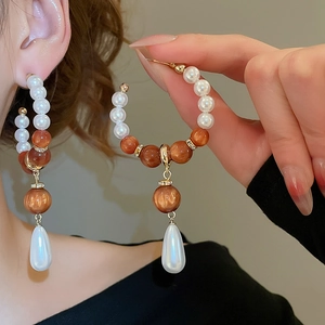 Detail of beaded drop earrings with white pearls and brown sparkling resin beads