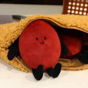 Detail of red peanut plush toy with cute face inside a yellow fleece zipper pouch