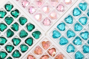 Macro view of multi-color heart-shaped crystal glass rhinestones in sorting trays