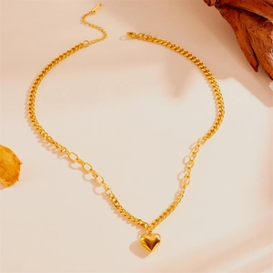 Collier doré avec pendentif cœur et chaînes mixtes sur un décor artistique en bois