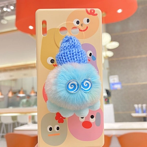 Detail der cremegelben Handyhülle mit blauem 3D-Plüschmonster und Cartoon-Prints