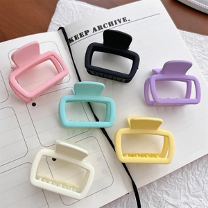 Set of 6 small square matte hair claw clips in assorted pastel colors on a notebook