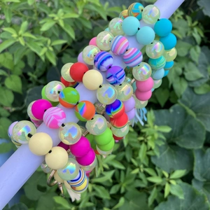 Colorful printed silicone bead bracelets with tassels displayed on a white tube outdoors