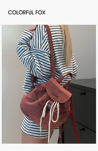 Reddish-brown nylon mini backpack with drawstring closure shown on model's back