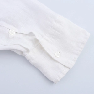Detailed close-up of white linen shirt cuffs featuring two buttons and premium texture