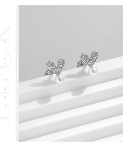 Close-up of 925 silver heart stud earrings with sparkling pavé crystals and white pearls