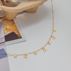 Elegante collana dorata a ciliegia con pendenti in zirconia su sfondo raffinato