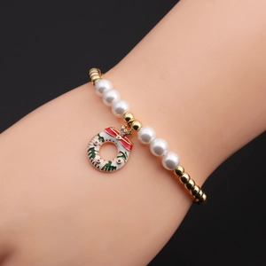 Gros plan d'un bracelet de Noël en perles avec un pendentif couronne de Noël en émail festif