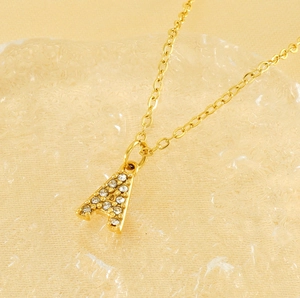 Gros plan d'un collier doré avec pendentif lettre A serti de petits strass brillants