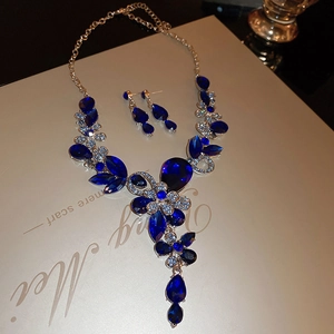 Macro shot of luxury gold necklace and earrings set with deep blue pear-shaped gems