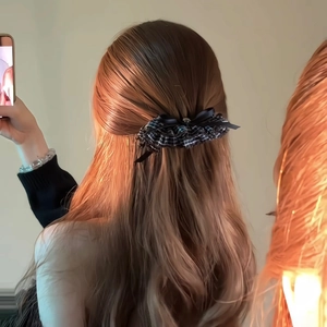 Detail showing checkered bow hair clip on dark brown hair with elegant retro style
