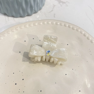 Creamy marble acetate bow hair clip with rainbow gemstone on ceramic plate