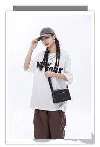 Close-up of black rectangular box bag styled with white New York t-shirt and cargo pants