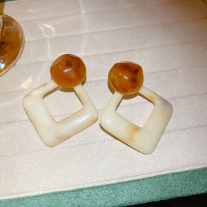 Detail of geometric resin drop earrings in amber brown and cream marble texture