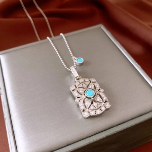 Detail of silver vintage pendant with sky blue stone and white diamonds on chain