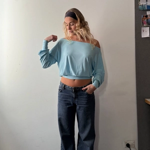 Slim-fit light blue off-shoulder long sleeve top paired with straight-leg blue jeans