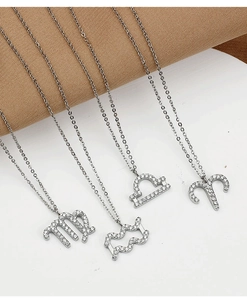 Detail of silver zodiac necklaces with sparkling zircon pavé on white surface