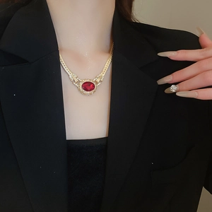 Detail of vintage gold necklace with oval red gemstone and crystal inlay worn on neck