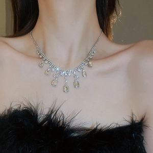 Close-up of a silver tassel necklace with rhinestones worn by a model in soft lighting