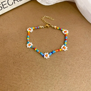 Close-up of colorful beaded daisy bracelet with yellow beads and gold lobster clasp