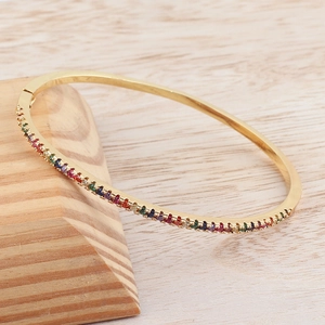 Macro detail of 18k gold plated oval bangle with multi-color rainbow cubic zirconia stones