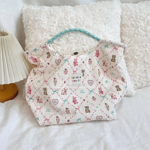 Detail of cartoon printed tote bag with cream wavy fabric and blue woven handles