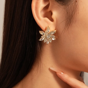 Macro view of crystal flower earrings featuring a multi-layered snowflake design on model