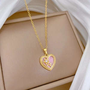 Macro detail of a gold heart pendant with pink enamel and sparkling floral diamond center