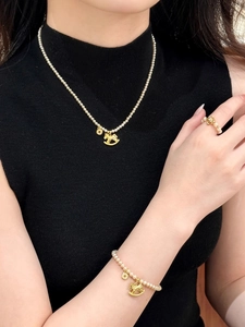 Elegant pearl bead necklace featuring a gold rocking horse and coin pendant on model