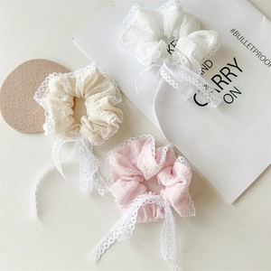 Detailed view of white, beige, and pink seersucker scrunchies with lace ribbons