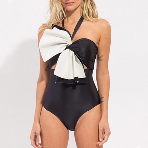 Classic black one-piece swimsuit with large white bow detail and halter neck style