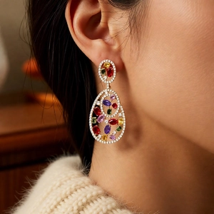 Close-up of model wearing vintage gold drop earrings with colorful zircon gemstones